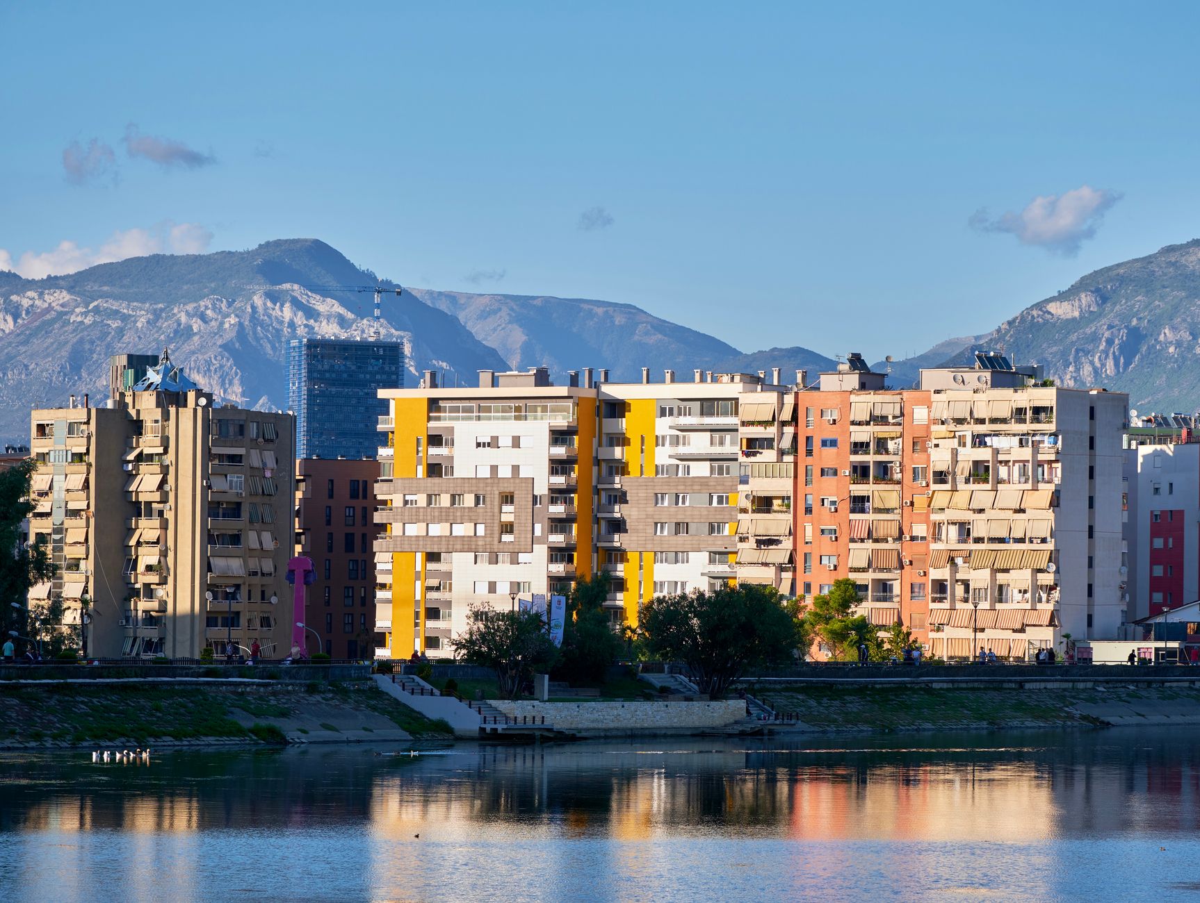 Immeubles colorés au bord de l'eau à Tirana, montagnes en arrière-plan