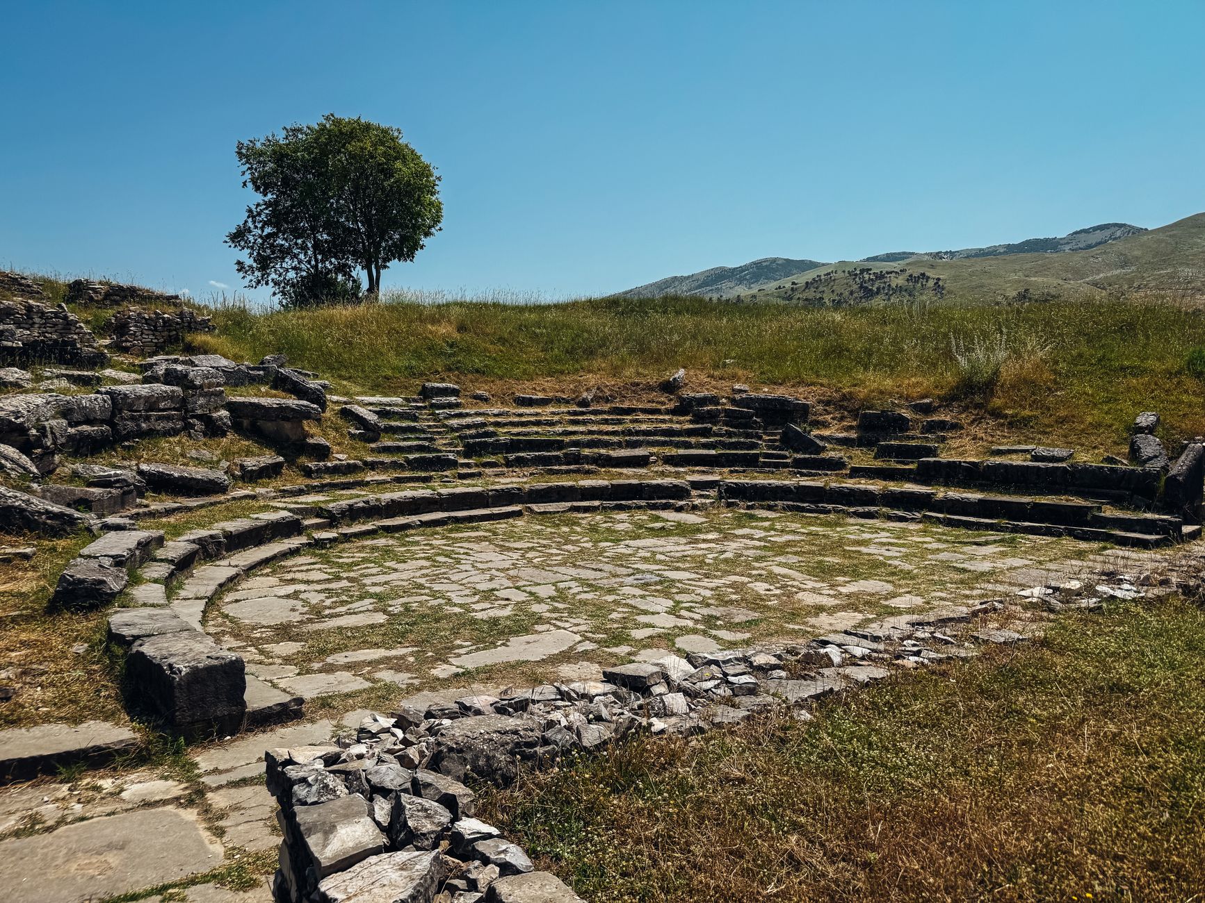 Gradins d'un théâtre antique envahis par la végétation, en Albanie
